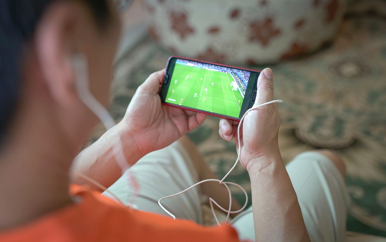 Man watching sports on smartphone device